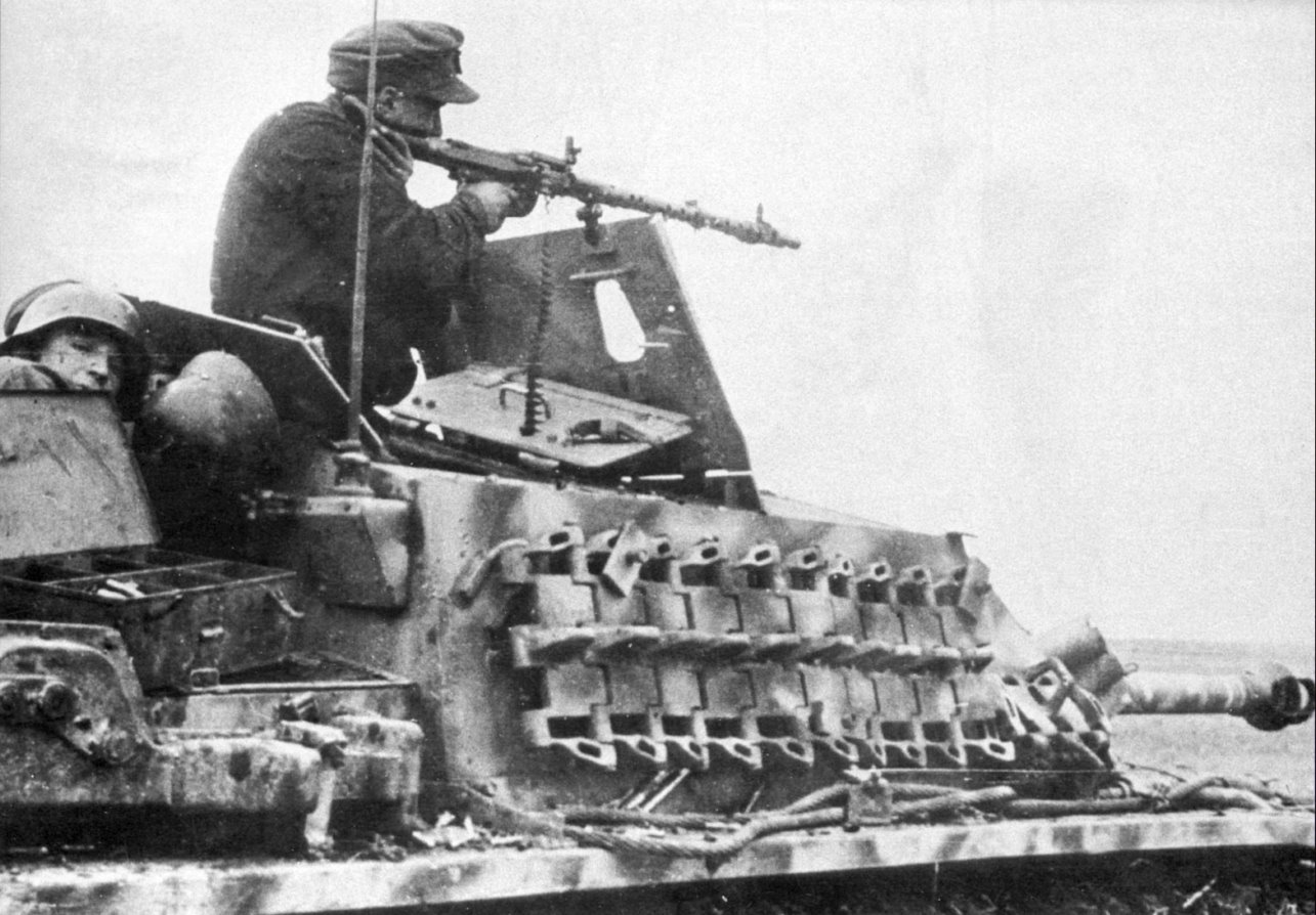 Немецкий танкист ведет огонь из пулемета MG-34 на САУ StuG III Ausf. G —  военное фото